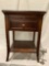 Wood nightstand with pull out surface and drawer, shows finish wear, approx 19 x 19 x 27 in.