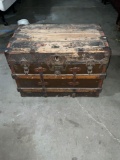 Antique wooden steamer trunk with brass detail, missing one leather handle