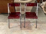 Pair of red lucite and aluminum folding chairs.