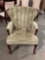 Vintage wingback chair with sage green leaf pattern upholstery and cabriole legs.