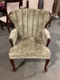 Vintage wingback chair with sage green leaf pattern upholstery and cabriole legs.