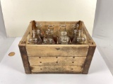 vintage milk crate filled with a variety of 12x glass milk bottles.