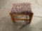 Padded foot stool with fabric top and designs in the fabric.