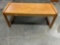 Wooden coffee table with wood grain top and beveled legs.