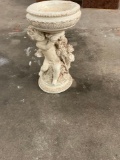 Garden statue cherub holding up bowl stand.