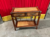 Vintage side table with weaving on the top and wood frame .