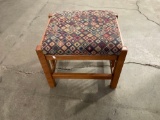 Padded foot stool with fabric top and designs in the fabric.
