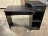 Black desk with laminate and drawer.