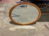 Wood frame oval mirror with beveled glass edges.