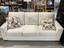 Modern Ashley Furniture Three Seat Couch w/ Cream Fabric Upholstery & Accent Pillows.