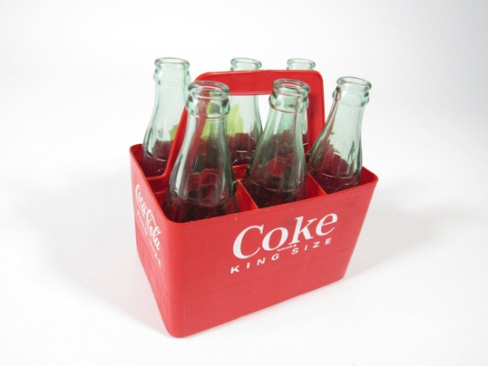 1960s Coca-Cola King Size plastic six-pack carrier with period glass bottles.