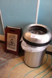 Stainless trash can with wet floor sign