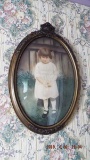 Oval painting of child in floral carved frame