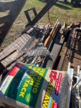 Wooden handle pole saw rakes, tomato racks, and bag of mulch