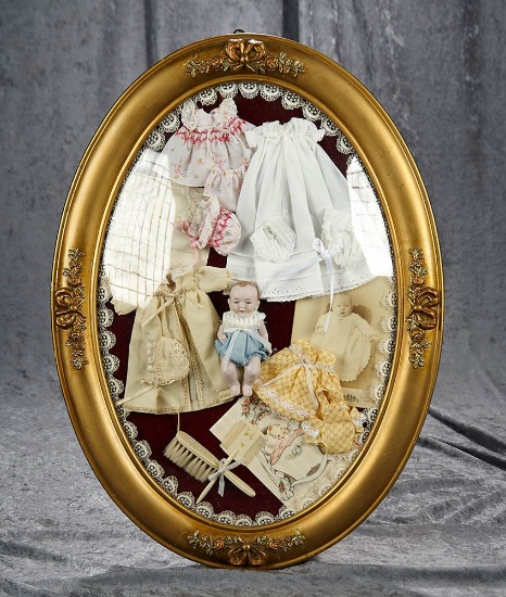 23"h. Victorian oval frame vignette under glass of bisque baby, costumes, accessories. $300/400