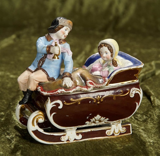 7"l. German porcelain trinket box "Little Girl with Her Doll in Winter Sleigh". $400/500