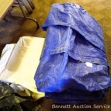 Large blue tarp and white tarp. White tarp has printing. Stack is approx. 3' by 2' by 1'.