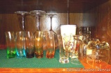 Assorted colored and clear bar glassware, plus a plastic Rum Chata cup.