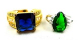 Two rings. Seller's description states 'green emerald ring, size 7; princess cut blue sapphire ring,