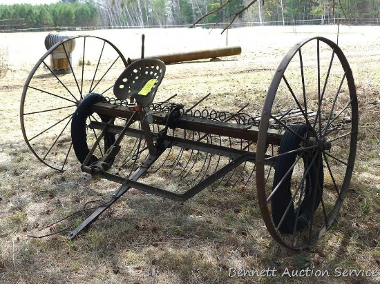Antique International Harvester horse drawn dump rake is 8' wide with 4-1/2' steel wheels.