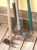 Spade shovel, rake, curved hoe and another hoe.
