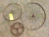Three antique steel wheels, largest is 2 ft.