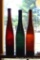 Green and brown glass wine bottles with divots in bottoms, plus one without. Tallest bottle is