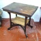 Antique parlor table has ceramic casters and original finish except for the bottom shelf, which has