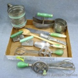 Vintage green handled kitchen utensils including beaters, choppers, sifters, scoop, spreader, jar