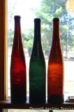 Green and brown glass wine bottles with divots in bottoms, plus one without. Tallest bottle is