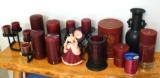Variety of cranberry colored candles, some with holders, plus a vase and figurine.