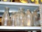 Collation of 8 clear glass bottles. Tallest stands 9 1/2