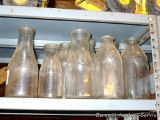 Collation of 8 clear glass bottles. Tallest stands 9 1/2