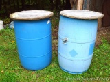 Two 55 gallon rain plastic rain barrels with screen tops. Both have faucets to drain into a pail.