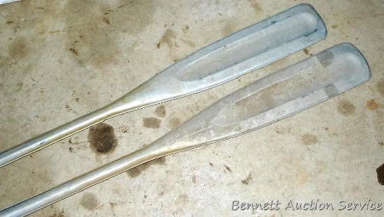Pair of stamped aluminum boat oars with oar locks. One has original wooden handle. 6-1/2'.