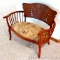 Wonderful antique love seat has curved arms and back, cut design to accent the back rest, applied