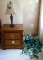 Solid wood end table with a nice little table lamp and wall hanging with faux greenery. End table is