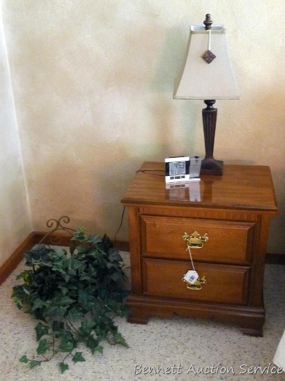 Solid wood end table with a nice little table lamp and wall hanging with faux greenery. End table is