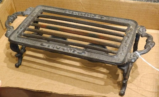 Cast iron trivet or warming plate has a place for two little candles. Measures 12" over handles.