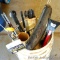 Five gallon bucket with ice fishing equipment including tip-ups, rods, braided nylon line, ice scoop