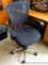 Newer style rolling office chair is comfortable and in overall good condition. One arm is loose, a