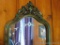 Antique wall mirror has floral/leaf design. Measures 24