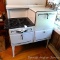 Very vintage Roper gas range is in great shape. Enamel is nice. Has four burners, stacked oven and