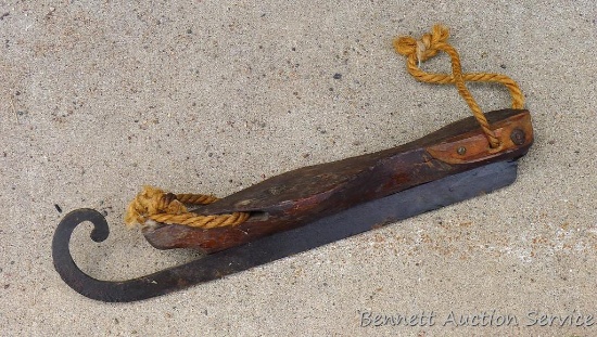 Antique skate has a wooden sole and forged iron blade and sisal rope bindings.