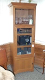 Lighted cabinet stands nearly 6' tall and has one pull out shelf and two others behind a glass door