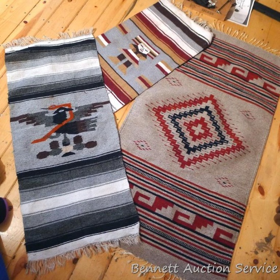 Three woven wall rugs. Largest rug is about 5' x 32" over fringe and has a couple holes noted.