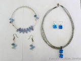 Two costume jewelry necklace and earring sets.