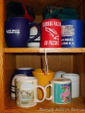 Assorted coffee mugs and can coozies.