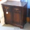 Wooden storage cabinet has 2 doors with 2 shelf storage inside. Measures 28