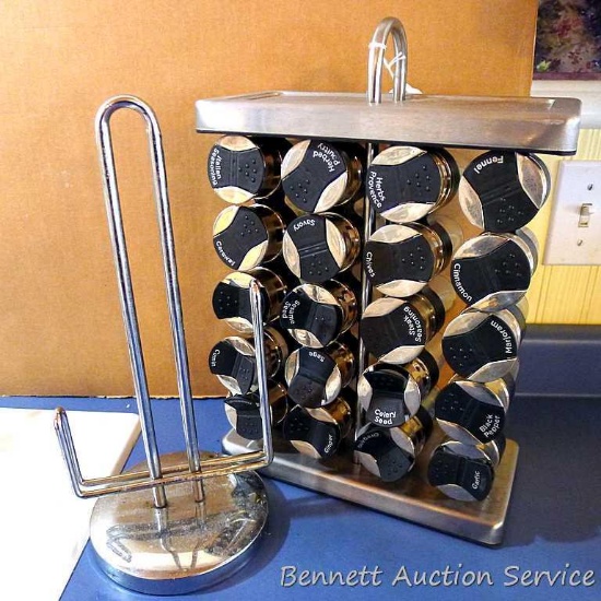 Freestanding spice rack has glass canisters neatly labeled. Unit measures 16" high x 10-1/2" x 5"